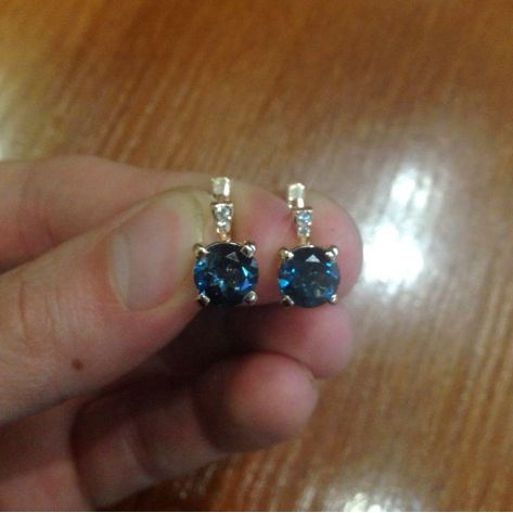 женские серьги с большими камнями в руке