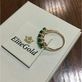 женское кольцо в белом золоте с зелеными камнями